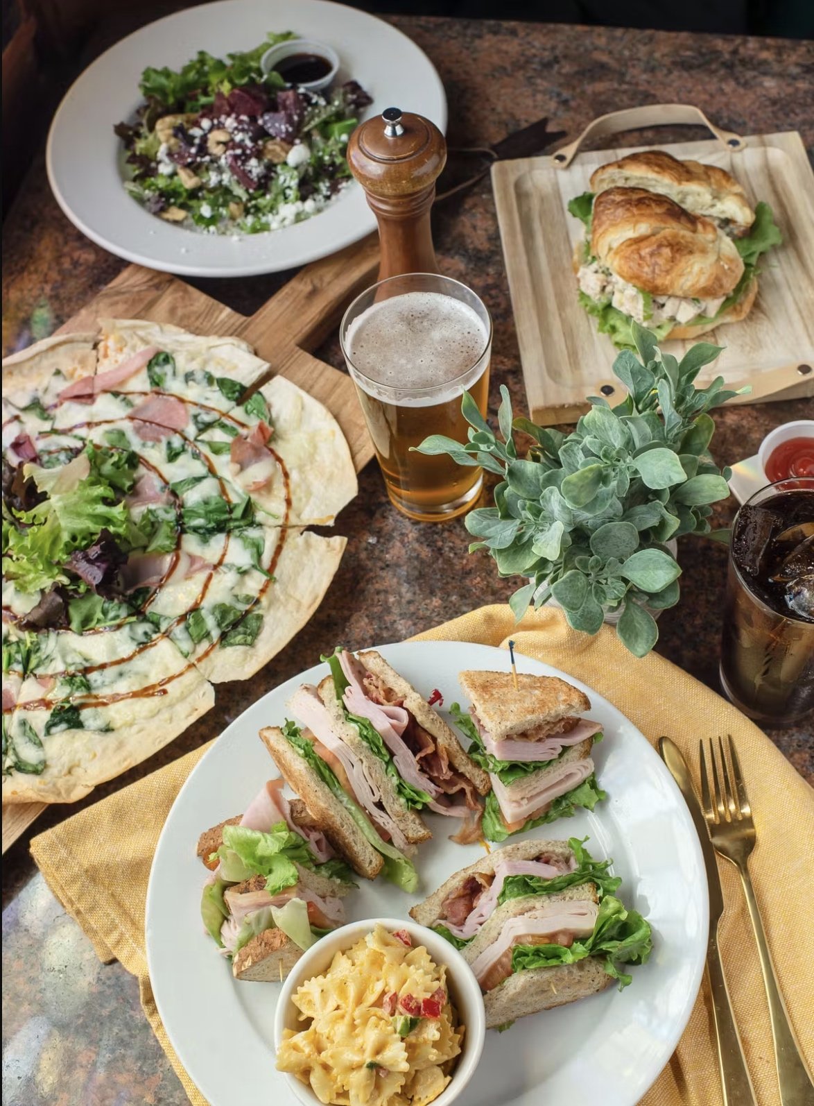 spread of lunch options with flatbread, salad, and sandwichies